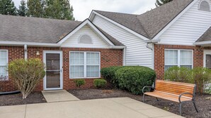 A residential house with a front porch, a bench, and a small garden area. - Keystone Garden Villa B (Indianapolis)
