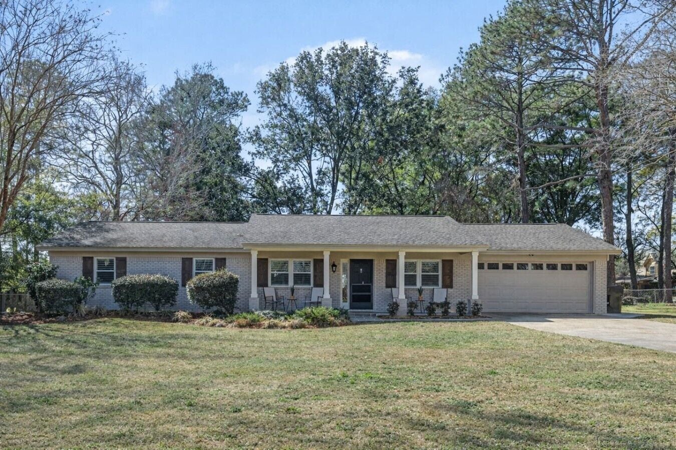 A single-story house with a front porch, a garage, and a well-maintained lawn.