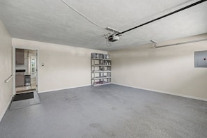 Ein Raum mit grauem Betonboden, einem an der Decke befestigten Projektor und einem Metallregal an der Wand.