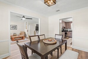 A dining area with a dark wooden table, six chairs, and a woven placemat. - 3BR Villa | 80` TV + Gazebo + Yard + King Suite (Tallahassee)