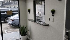 Interior moderno com uma planta em vaso, uma prateleira com relógio e uma porta que dá para o exterior.