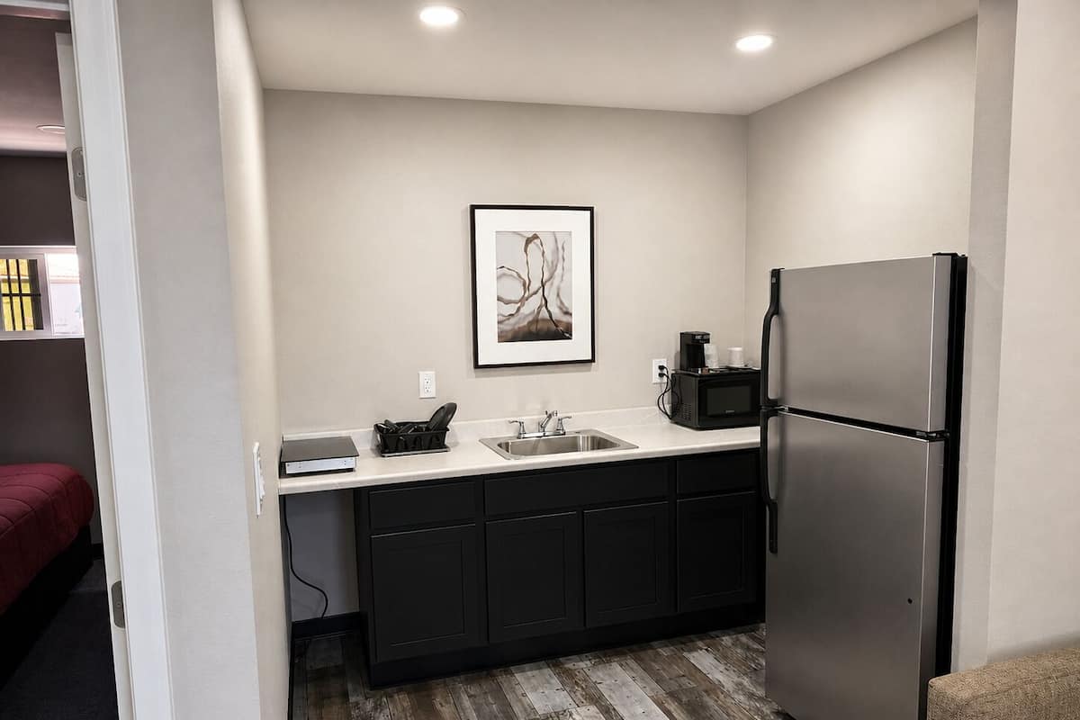 A compact kitchen with a stainless steel refrigerator, a microwave, and a sink.