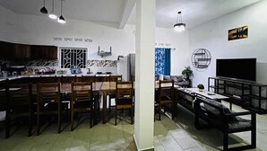 Una cucina moderna con zona pranzo, caratterizzata da un'isola centrale, sedie in legno e illuminazione a sospensione.