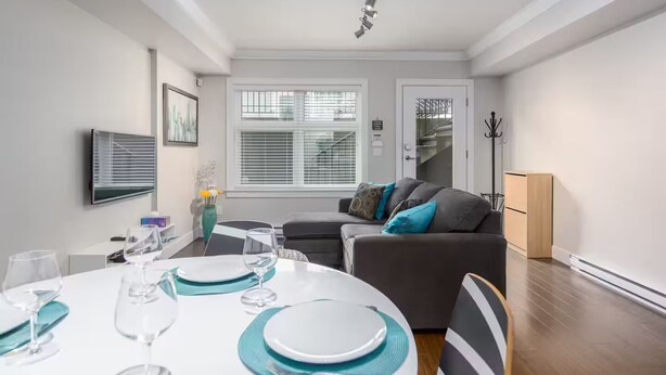 Een moderne woonkamer met een bank, een eettafel gedekt voor twee personen, en een trap naar een verdieping.