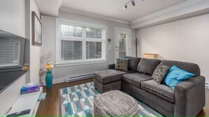 Een woonkamer met een modulaire bank, een salontafel, een vaas met bloemen en een kamerbreed tapijt met patroon.