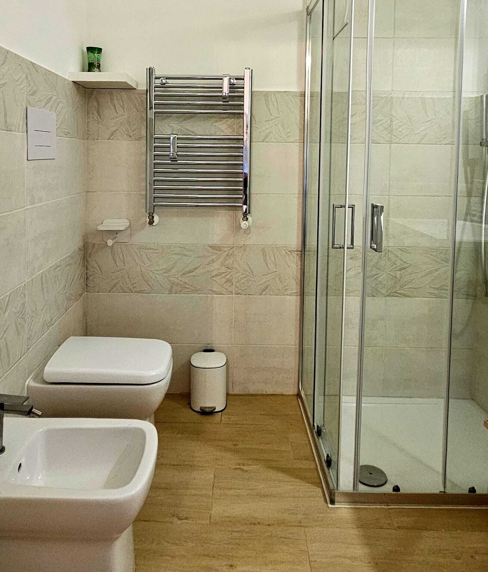 Un bagno con WC, bidet e box doccia in vetro.