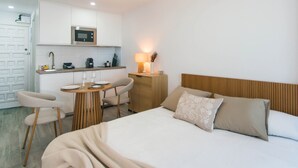 Une chambre d’hôtel comprenant un lit, une table de chevet, une lampe et un coin cuisine équipé d’un four à micro-ondes.