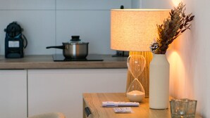 Un comptoir de cuisine avec une lampe, un vase contenant des fleurs séchées, un verre et une bouilloire.