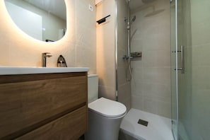 A modern bathroom with a wooden vanity, a white toilet, a glass shower enclosure, and a large mirror. - WELCS ESTUDIO 1001 PDA with ocean view (Gerona/Girona)