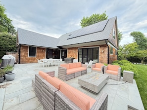 A modern house with a patio area featuring outdoor furniture, a fireplace, and a covered barbecue area. - US Open Golf Championship Rental - modern 4-bedroom house in serene East Hampton (East Hampton)