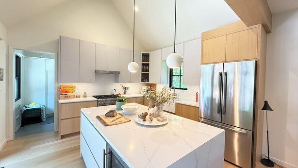 Una cucina moderna con un'isola grande, elettrodomestici in acciaio inossidabile e luci a sospensione.