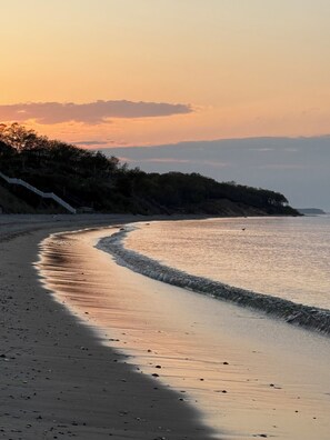 A beach with a curved shoreline, a staircase leading up to a wooded area, and a calm sea. - US Open Golf Championship Rental - modern 4-bedroom house in serene East Hampton (East Hampton)