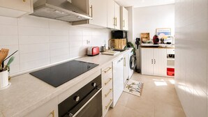A modern kitchen with white cabinetry, a black induction cooktop, and a built-in oven. - Apartment for 4 people - golf course view - La Torre Golf Resort (Torre-Pacheco)