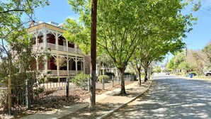 A street with a two-story building, trees, and a sidewalk. - King William Historic District Cozy 3BR SATX (San Antonio)