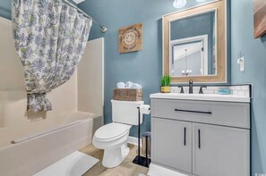 A bathroom with a bathtub, toilet, and vanity with a mirror. - Tee Off & Hit the Beach – NMB Barefoot Resort, 2BR, 5 Minutes from Shore (North Myrtle Beach)