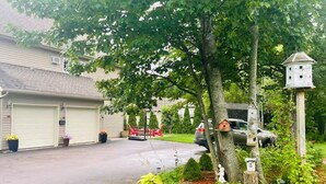 Uma entrada residencial com garagem, uma árvore e casas de passarinho.