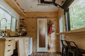 Une cuisine compacte avec des meubles en bois, un évier et une fenêtre donnant sur un espace verdoyant.