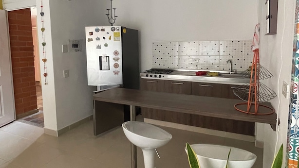 A modern kitchen with a white refrigerator, gas stove, and two white bar stools.
