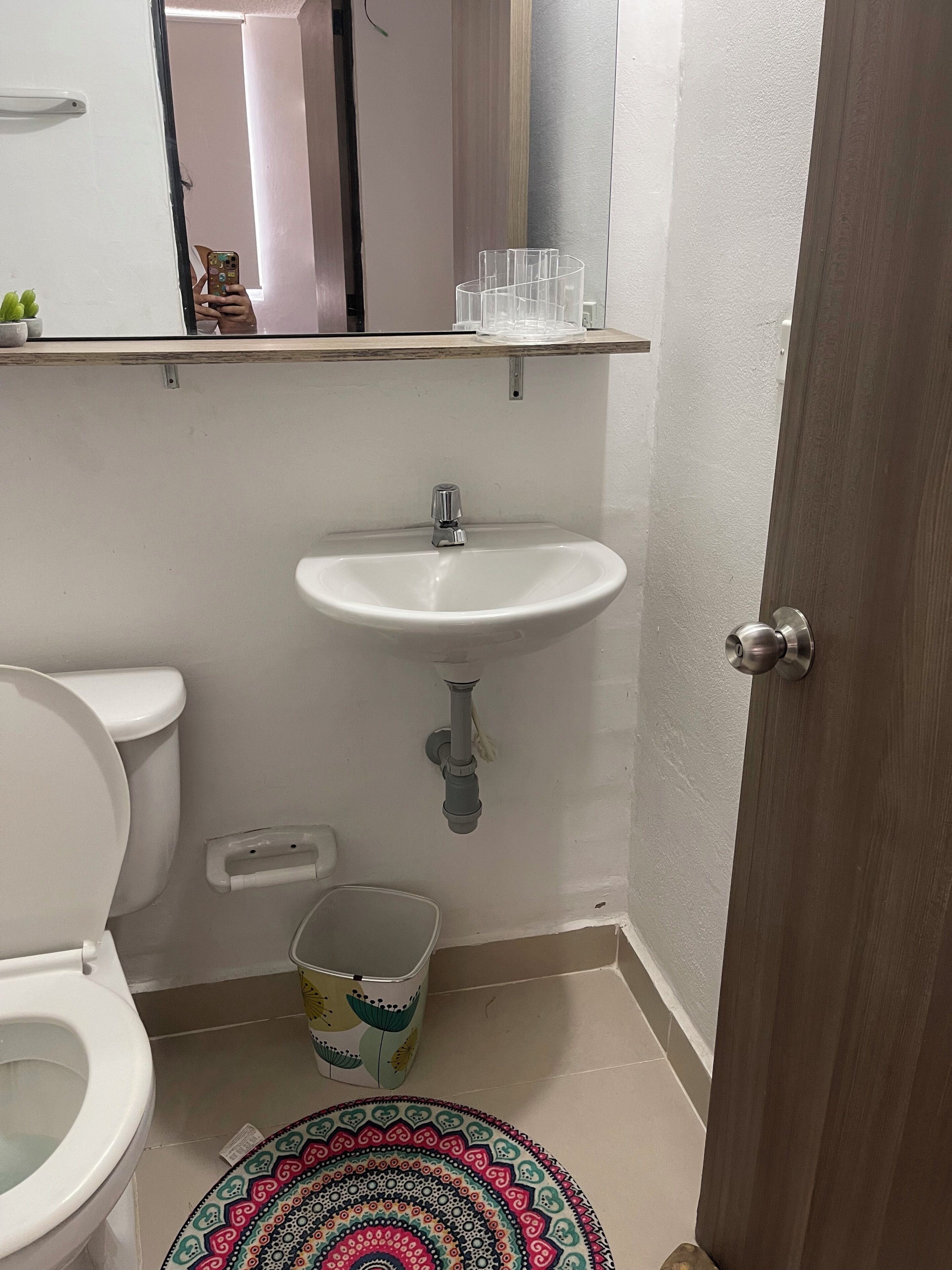 Casa de banho com sanita, lavatório e um pequeno contentor de lixo.