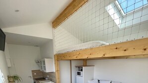 A compact living space with a kitchenette, a sofa, a dining table, and a small stool. - Detached 2-star studio, sleeps 4, very quiet, close to the seafront (Pisany)