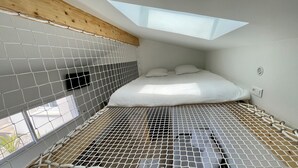 A compact room with a bed, a skylight, and a window. - Detached 2-star studio, sleeps 4, very quiet, close to the seafront (Pisany)