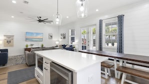 Cozinha moderna com ilha central, armários brancos e iluminação pendente.