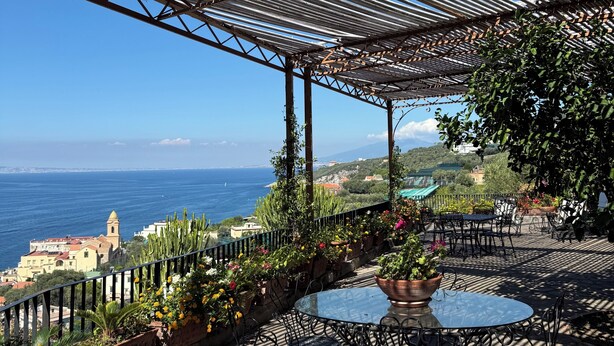 Un espace extérieur abrité, avec une table et des chaises, offrant une vue sur la côte.