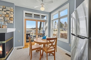 A kitchen with a fireplace, dining table, chairs, and a view of a lighthouse. - Waterview Studio at Beach, Pools (Manistee)