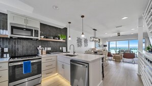 Een moderne keuken met een centraal eiland, roestvrijstalen apparatuur en een eethoek met uitzicht.