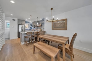 Een moderne keuken met een centraal eiland, een houten eettafel en stoelen.