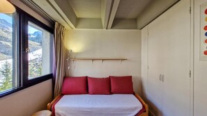 Ein kleines Schlafzimmer mit Bett, Fenster und Ausblick nach draußen.