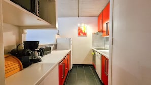 Eine kleine Küche mit Kaffeemaschine, Toaster und Kühlschrank.