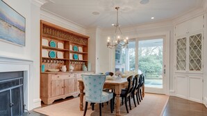 A dining area with a wooden cabinet, a chandelier, and a view through a glass door. - EAST HAMPTON VILLAGE JEWEL BOX (East Hampton)