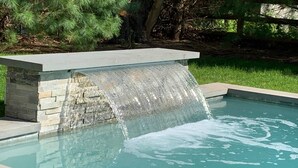 A swimming pool with a stone waterfall feature. - EAST HAMPTON VILLAGE JEWEL BOX (East Hampton)