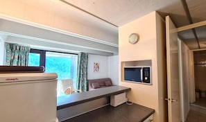 A compact room with a kitchenette, a bed, a window with curtains, and a microwave on the wall. - 100m from resort center, 8th floor, balcony, tv, 45m², Flaine (Flaine)