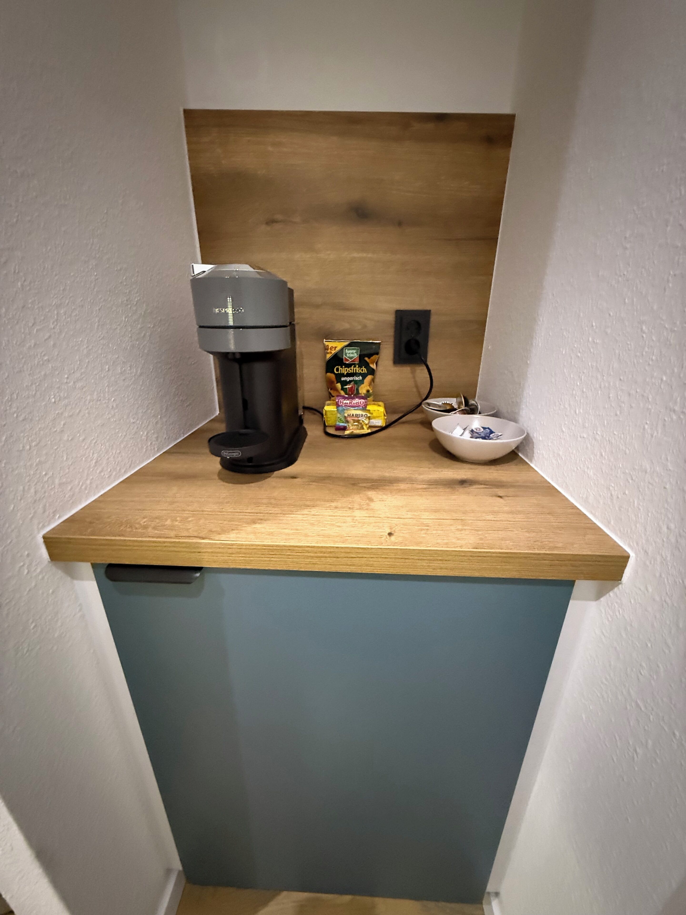 A kitchenette with a coffee maker, a bag of chips, and a bowl.