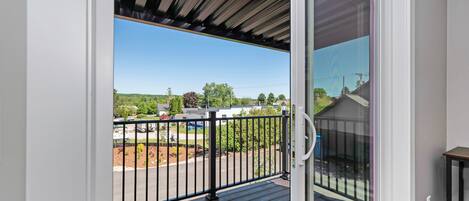 A balcony with a view of a parking lot and buildings.