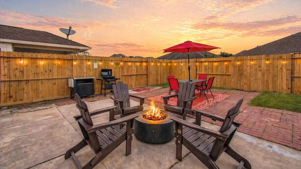 Un patio trasero con un brasero, mobiliario exterior y una valla de madera.