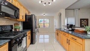 Una cocina moderna con armarios de madera, un refrigerador de acero inoxidable, una estufa negra y un ventanal amplio.