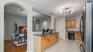 Una cocina moderna con armarios de madera, un refrigerador y una zona de comedor con televisión.