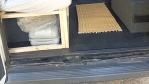 Un espacio habitable pequeño con cama, una kitchenette y un área de almacenamiento.