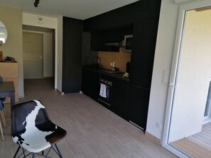 A modern kitchen with black cabinets, a built-in oven, and a small countertop. There is a chair with a black and white pattern in the foreground. - 300m from shops, Ground floor, parking, tv, ski locker, 49m², Pra Loup (Barcelonnette)