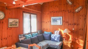 Interior acollidor d'una cabana amb elements de fusta, un sofà, una taula de dinar i una làmpada.