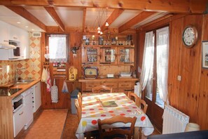 Ein Holzblockhaus-Interieur mit Küche, Essbereich und einer Uhr an der Wand.