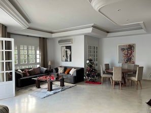 Amplia sala de estar con sofá, mesa de centro y comedor con sillas.