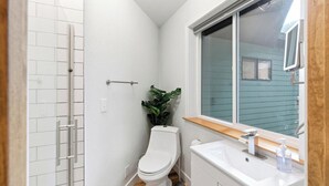 Ein Badezimmer mit Toilette, Waschbecken, Fenster und Pflanze.