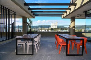 Eine Dachterrasse mit Außenmöbeln, einer Pergola und Blick auf die Stadtlandschaft.