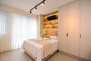 Ein modernes Schlafzimmer mit Bett, Nachttischen, einem Kleiderschrank und einer eingebauten Ablage mit Dekoration.