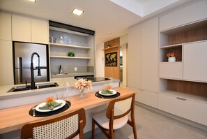Une cuisine moderne avec un coin repas, comprenant un four encastré, un évier et une table à manger en bois avec des chaises.