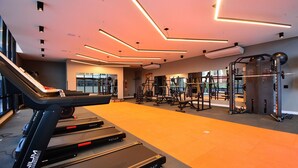 A modern gym with treadmills, weight machines, and a large mirror. - Elegante Studio frente a UFSC e HU -201R (Florianópolis)